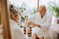 Senior couple in bathrobes enjoying time together in their living room, drinking hot tea, calm and hygge atmosphere. Royalty Free Stock Photo