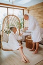 Senior couple in bathrobes enjoying time together in their living room, drinking hot tea, calm and hygge atmosphere. Royalty Free Stock Photo