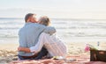 Senior couple, beach picnic and kiss with hug, romance and happiness in summer for anniversary celebration. Elderly man