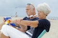 senior couple on beach woman applying suncream