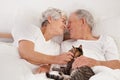 Senior couple, bed and cat for bonding, embrace and love in morning for smile and cuddle. Mature man, woman and kitty Royalty Free Stock Photo