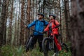 Senior couple bikers with e-bikes admiring nature outdoors in forest in autumn day.