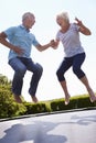 Senior Couple Bouncing On Trampoline In Garden Royalty Free Stock Photo