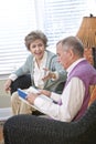 Senior couple chatting in living room reading book