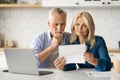 Senior Couple Checking Financial Documents While Sitting In Kitchen At Home Royalty Free Stock Photo