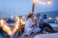 Senior couple cheering with champagne on a sailboat during wedding anniversary vacation - Old people having fun together drinking