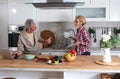 Senior couple cooking dinner together in the kitchen for golden wedding anniversary, reading recipe from internet on laptop. Older Royalty Free Stock Photo