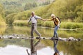 Senior Couple Crossing River Whilst Hiking In UK Lake District