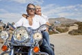 Senior couple on desert road sitting on motorcycle Royalty Free Stock Photo