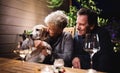 Senior couple with dog in the evening on terrace, drinking wine. Royalty Free Stock Photo