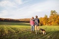 Senior couple with dog on a walk in an autumn nature. Royalty Free Stock Photo