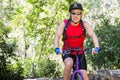 Male cyclist riding purple mountain bike on wooded trail wearing red top and hydration pack Royalty Free Stock Photo