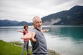 Senior couple doing outdoor yoga, tai chi, pilates by the lake in the autumn. Elderly husband and wife spending active Royalty Free Stock Photo