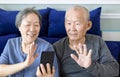 Senior couple doing video call via app on mobile phone at home