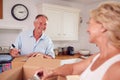 Senior Couple Downsizing In Retirement Packing And Labelling Boxes Ready For Move Into New Home