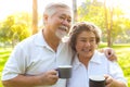 Senior couple drinking hot coffee or tea at park with happiness. Senior man and elderly woman hold cup of coffee, walking at park Royalty Free Stock Photo