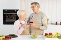 Senior Couple Drinking Wine Celebrating Family Holiday Standing In Kitchen Royalty Free Stock Photo