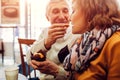 Senior couple eating cupcakes in cafe and drinking coffee. Man feeding his wife. Celebrating anniversary. Family values