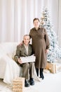 Senior couple in elegant clothes, celebrating New Year and Christmas at home in front of Christmas tree. Handsome Royalty Free Stock Photo