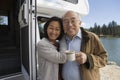 Senior couple embracing outside of RV on lake Royalty Free Stock Photo