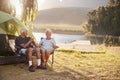 Senior Couple Enjoying Camping Vacation By Lake Making A Toast Royalty Free Stock Photo