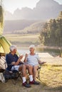 Senior Couple Enjoying Camping Vacation By Lake Making A Toast Royalty Free Stock Photo