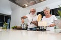 Senior couple enjoying and cooking healthy dinner together at home - Happy mature people preparing food to dine in the kitchen - Royalty Free Stock Photo