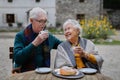 Senior couple enjoying cup of coffee and cake outdoor in cafe. Royalty Free Stock Photo