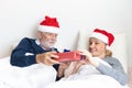 Senior couple exchange gift in their bed during the christmas