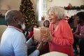 Senior Couple Exchanging Gifts As They Celebrate Christmas At Home With Family Royalty Free Stock Photo