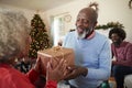 Senior Couple Exchanging Gifts As They Celebrate Christmas At Home With Family Royalty Free Stock Photo