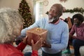 Senior Couple Exchanging Gifts As They Celebrate Christmas At Home With Family Royalty Free Stock Photo