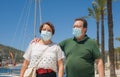 Senior couple with face mask on holidays during covid19 - happy and sweet mature husband and wife enjoying retirement walking on Royalty Free Stock Photo