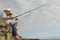 Senior Couple Fishing Against Cloudy Sky