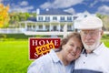 Senior Couple in Front of Sold Real Estate Sign and House Royalty Free Stock Photo