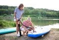 Senior couple getting ready for paddleboarding by lake in summer.