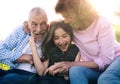 Senior couple with granddaughter outside in spring nature, relaxing on the grass. Royalty Free Stock Photo