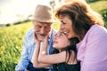 Senior couple with granddaughter outside in spring nature, relaxing on the grass. Royalty Free Stock Photo