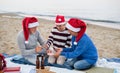 Senior couple with granddaugter celebrate New Year or Christmas and have picnic on beach. Royalty Free Stock Photo