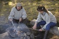 Senior couple grilling sausages over camp fire Royalty Free Stock Photo