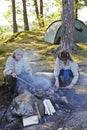 Senior couple grilling sausages over camp fire Royalty Free Stock Photo