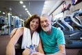 Senior couple in gym sitting in front of treadmills