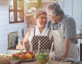 Senior couple having fun in kitchen with healthy food - Retired people cooking meal at home with man and woman preparing lunch Royalty Free Stock Photo