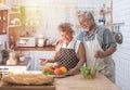 Senior couple having fun in kitchen with healthy food - Retired people cooking meal at home with man and woman preparing lunch Royalty Free Stock Photo