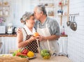 Senior couple having fun in kitchen with healthy food - Retired people cooking meal at home with man and woman preparing lunch Royalty Free Stock Photo