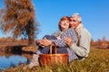 Senior couple having picnic by autumn lake. Happy man and woman enjoying nature and hugging Royalty Free Stock Photo