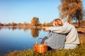 Senior couple having picnic by autumn lake. Happy man and woman enjoying nature and hugging Royalty Free Stock Photo