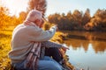 Senior couple having picnic by autumn lake. Happy man and woman enjoying nature and hugging Royalty Free Stock Photo