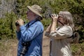 Senior Couple Hiking and Birdwatching in Woods on a Sunny Day