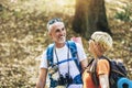 Couple hiking in forest wearing backpacks and hiking poles. Nordic walking, trekking. Healthy lifestyle Royalty Free Stock Photo